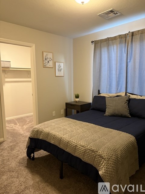 A bedroom with a bed, nightstand, and window.