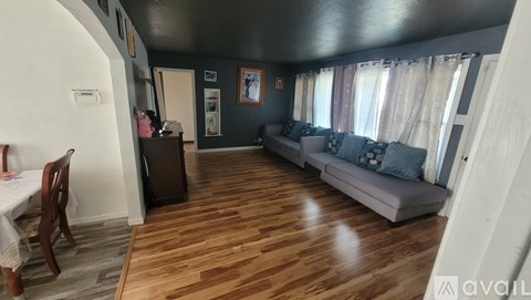 A living room with a grey couch and wooden floors.