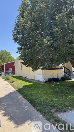 A tree in front of a house with a red roof.