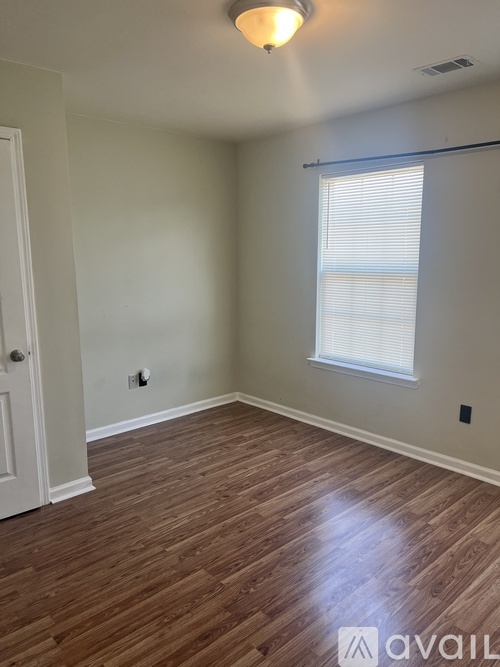 A room with wooden flooring and a window with blinds.
