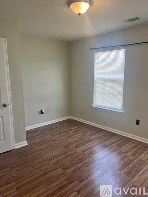 A room with wooden flooring and a window with blinds.