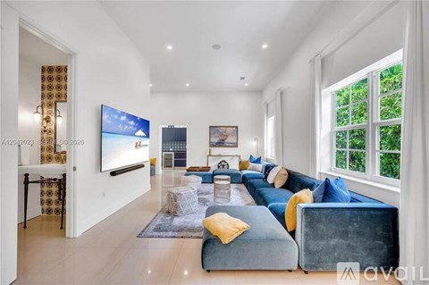 A living room with a blue couch and a television on the wall.