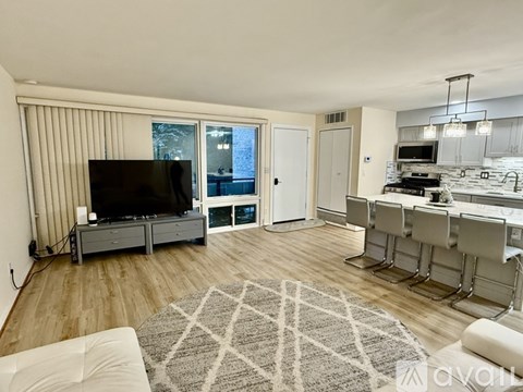A living room with a television, a dining table, and chairs.