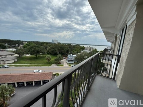 A balcony overlooks a street with cars and houses.