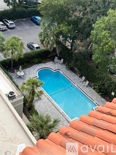 A pool surrounded by trees and a parking lot.