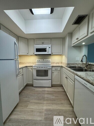 A kitchen with white appliances and cabinets.