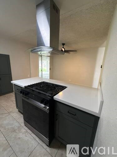 A kitchen with a black stove top oven and a black cabinet.