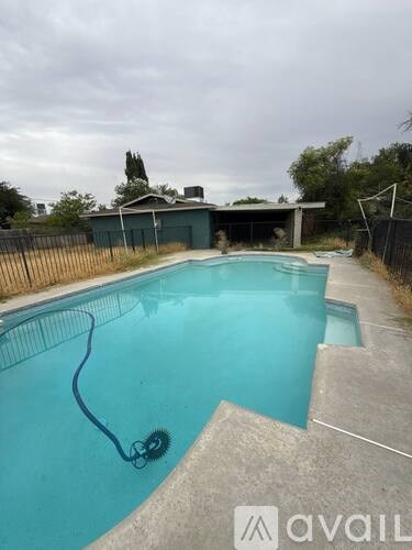 A pool with a black fence and a house in the background.
