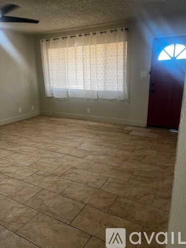 A room with a tiled floor and a window with curtains.