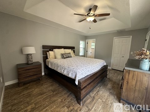 A bedroom with a bed, dresser, and ceiling fan.