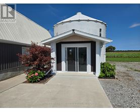 A white building with a gravel driveway in front.