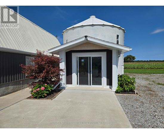 A white building with a gravel driveway in front.