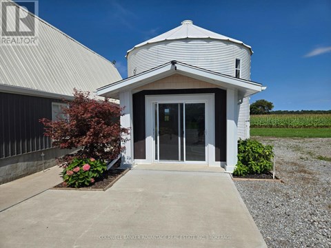 A white building with a gravel driveway in front.