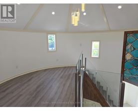 A large open space with a wooden floor and a staircase with a glass railing.