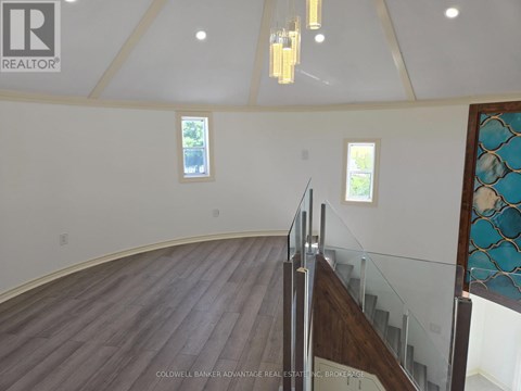 A large open space with a wooden floor and a staircase with a glass railing.