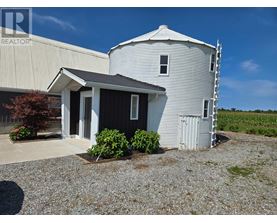 A grain silo stands next to a small house with a porch.