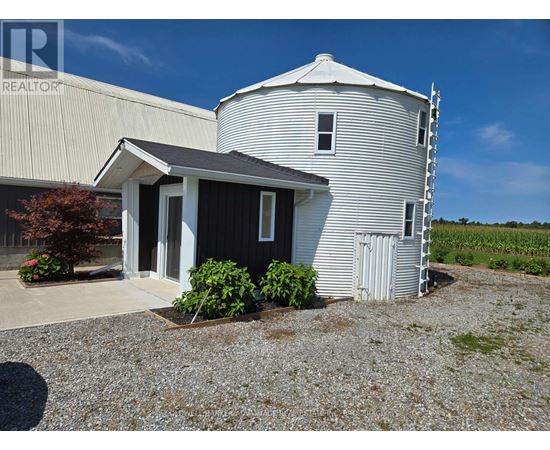 A grain silo stands next to a small house with a porch.