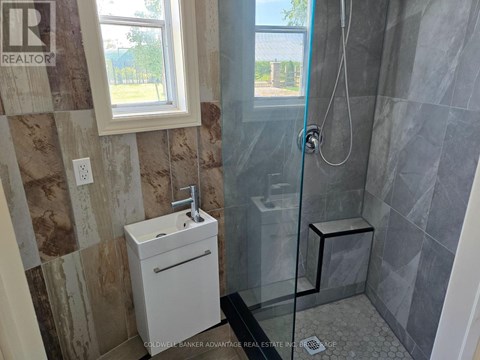 A bathroom with a glass shower stall and a white sink.
