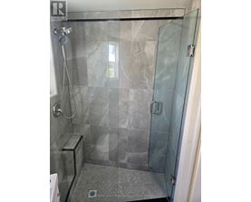 A shower area with a glass door and a glass wall.