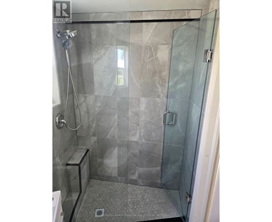 A shower area with a glass door and a glass wall.