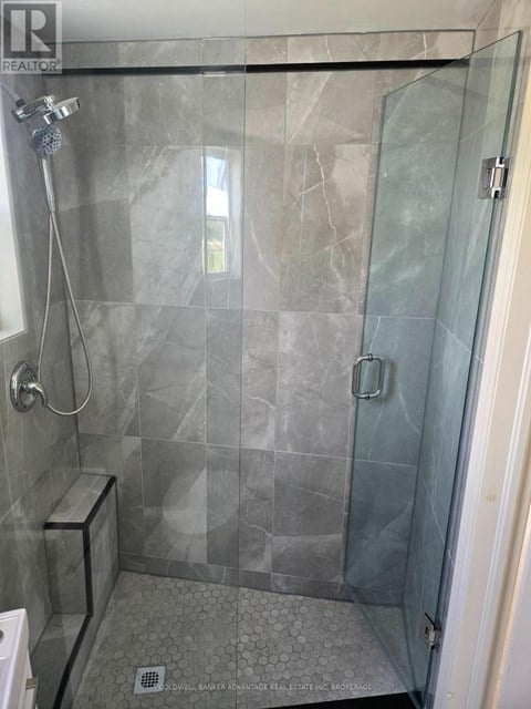 A shower area with a glass door and a glass wall.