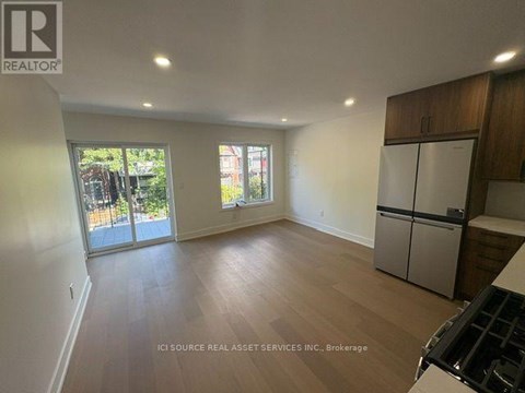 A spacious kitchen with wooden floors and a refrigerator.