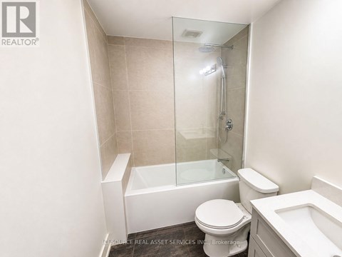 A white toilet sits next to a white bathtub in a bathroom.