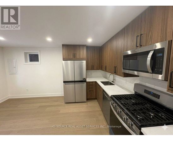 A kitchen with a stainless steel refrigerator, microwave, and oven.