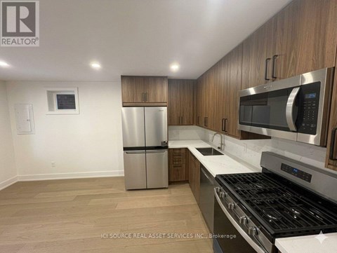 A kitchen with a stainless steel refrigerator, microwave, and oven.