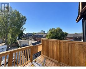 A wooden deck with a bench overlooks a residential area.