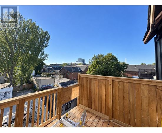 A wooden deck with a bench overlooks a residential area.
