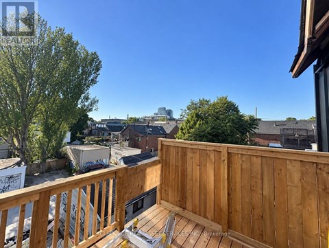 A wooden deck with a bench overlooks a residential area.