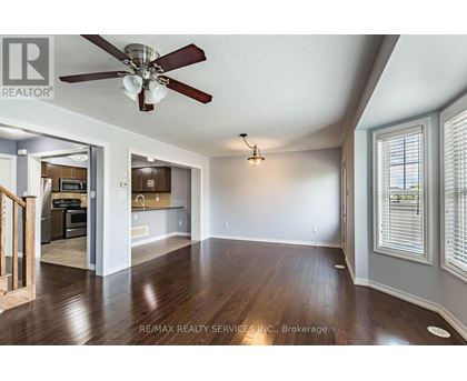 A spacious room with a ceiling fan and hardwood floors.