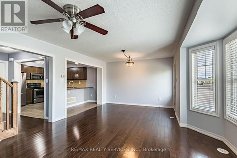 A spacious room with a ceiling fan and hardwood floors.