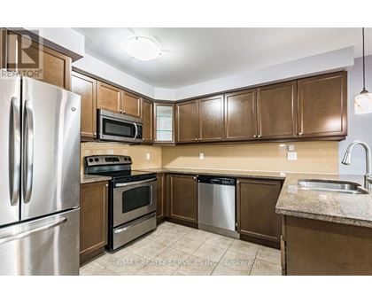 A kitchen with brown cabinets and a stainless steel refrigerator.