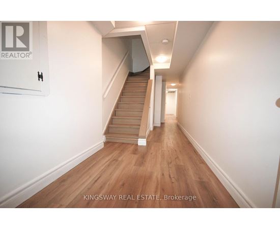 A hallway with a staircase and a sign that says "Kingsway Real Estate Brokerage".
