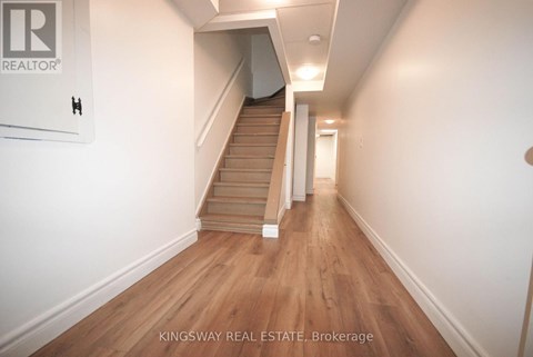 A hallway with a staircase and a sign that says "Kingsway Real Estate Brokerage".