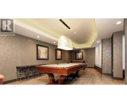 A pool table in a room with a brown wall and a painting hanging on it.