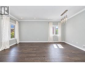 A spacious room with wooden flooring and white curtains.