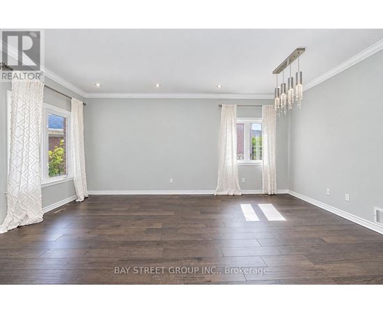 A spacious room with wooden flooring and white curtains.