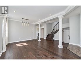 A spacious living room with wooden floors and a staircase.
