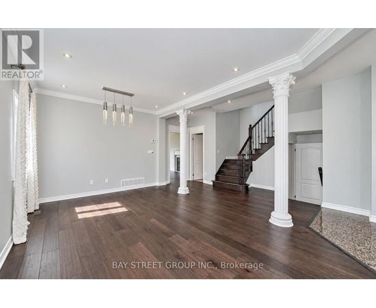 A spacious living room with wooden floors and a staircase.