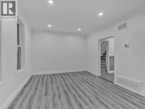 A spacious room with wooden flooring and white walls.