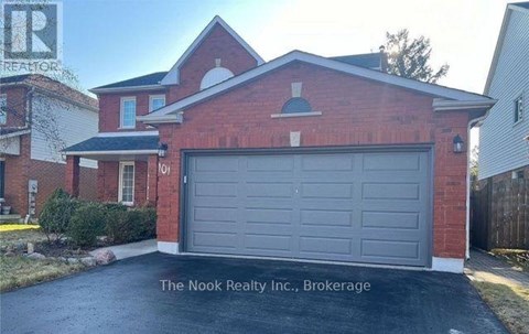 A red brick house with a grey garage door in front.