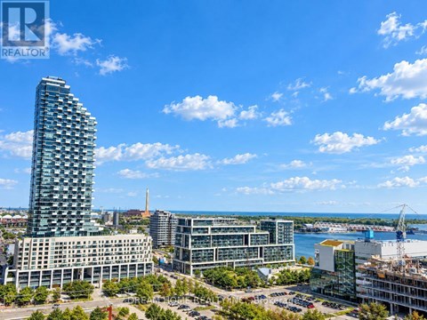 A cityscape with a tall building in the foreground and a body of water in the background.