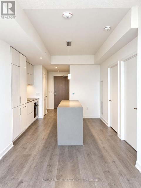 A modern kitchen with white cabinets and a wooden floor.