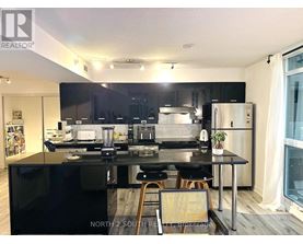 A modern kitchen with black countertops and stainless steel appliances.