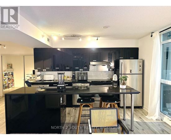 A modern kitchen with black countertops and stainless steel appliances.