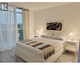 A bedroom with a large bed, a nightstand, and a painting on the wall.