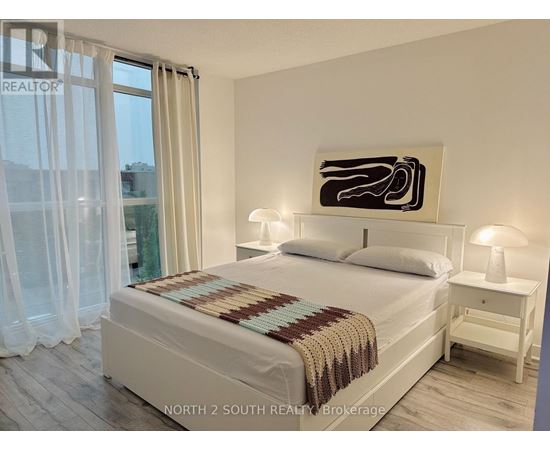 A bedroom with a large bed, a nightstand, and a painting on the wall.